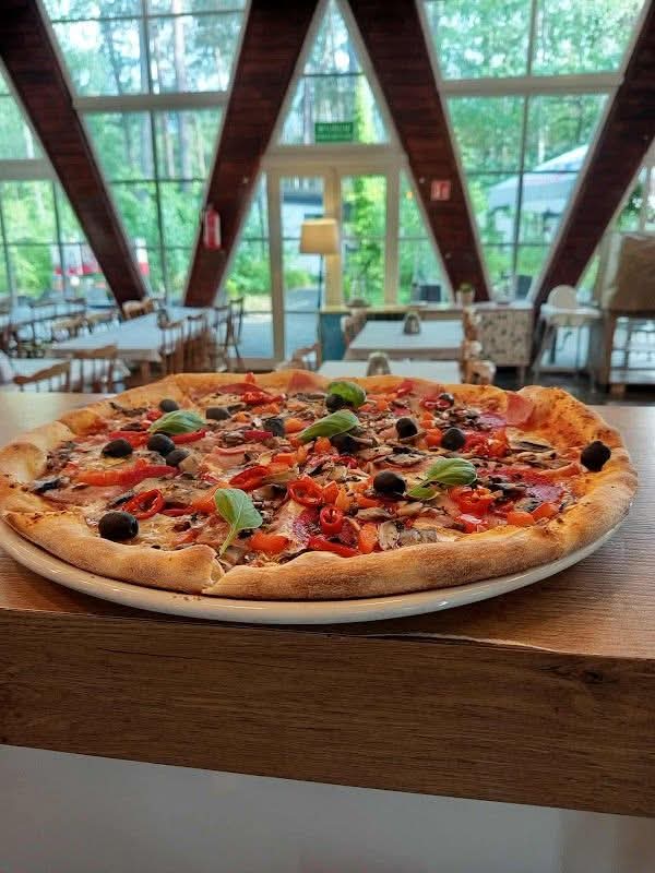 Pizza na tle wnętrza pizzerii Bursztynowo z trójkątnymi oknami